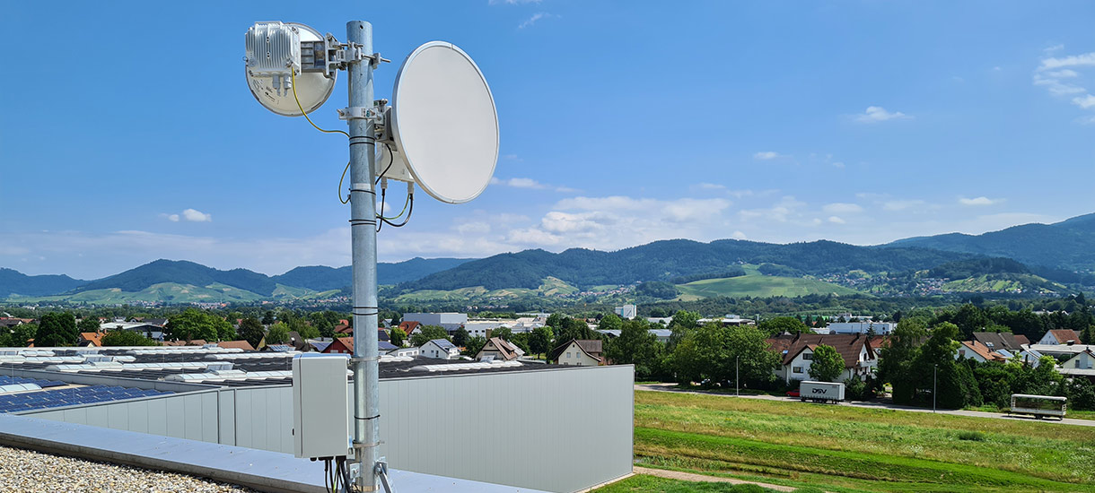 Richtfunkantenne vor einer begrünten Landschaft