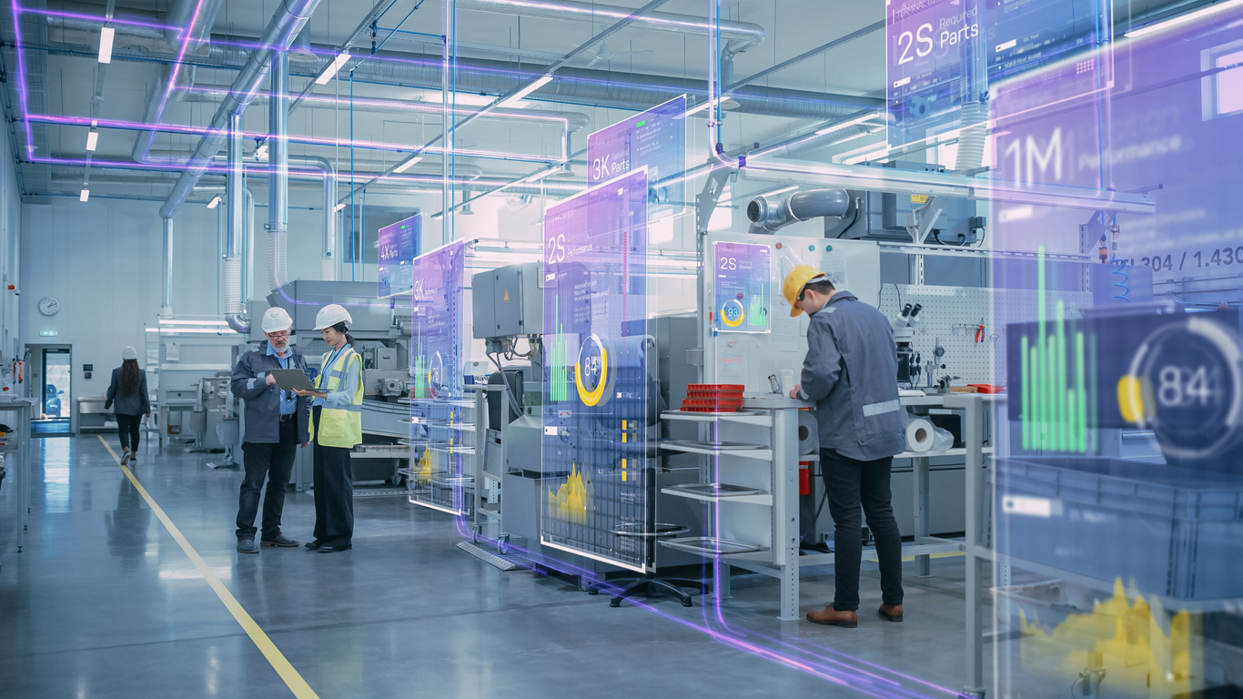 Produktionshalle in der Industrie mit digitalen Monitoren, die Kennzahlen anzeigen.