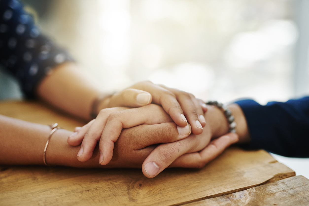 Pflegerin hält einem älteren Menschen die Hand
