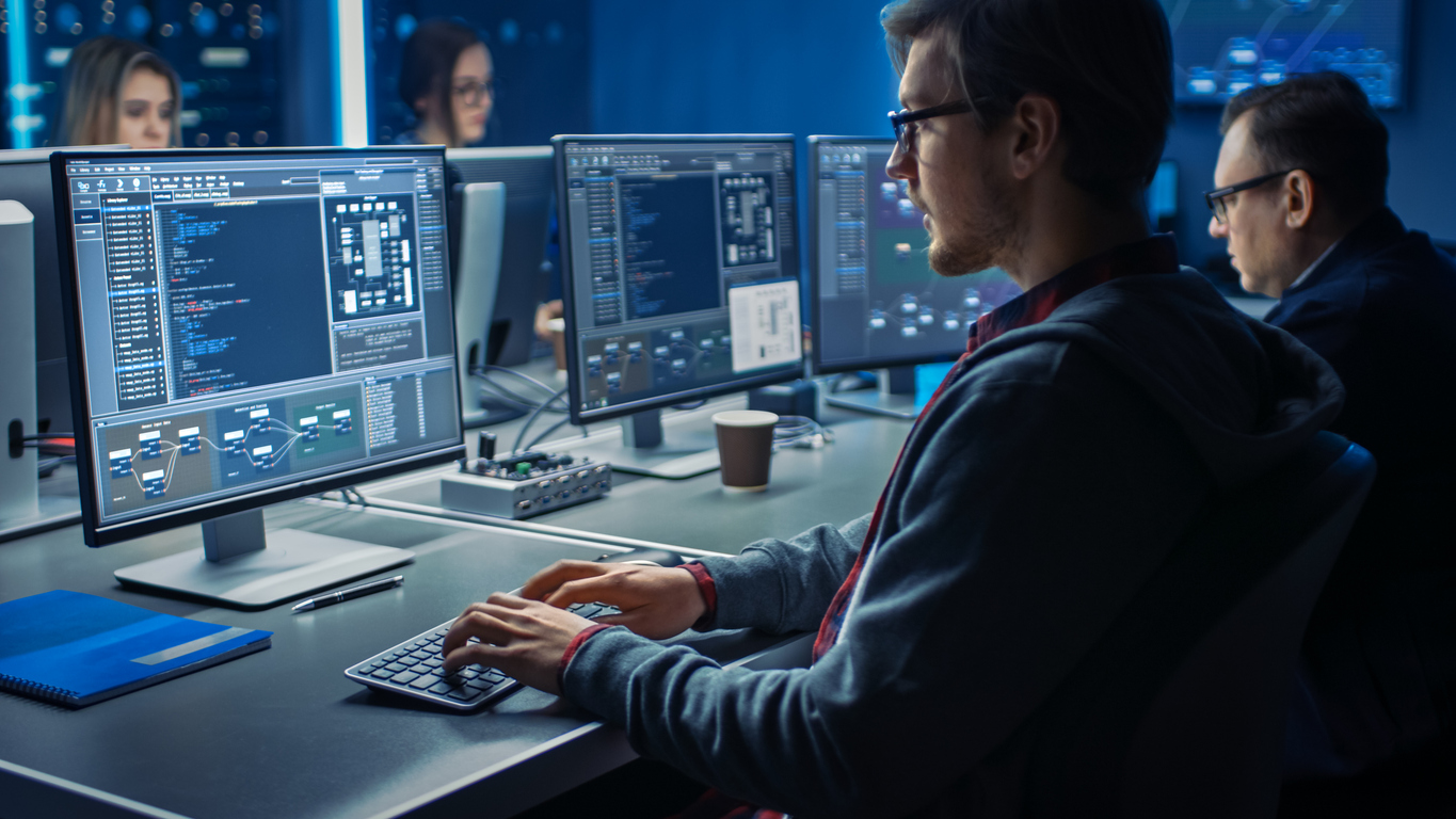 Mehrere Personen sitzen vor Bildschirmen in einem Security Operations Center