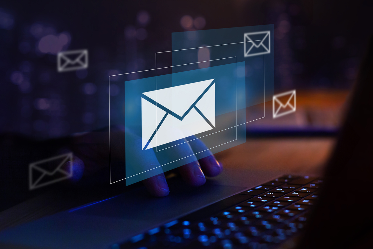 Spam & Malware Schutz Hand auf einer Laptoptastatur im Hintergrund mehrere visualisierte E-Mail / Brief Symbole mittig im Bild
