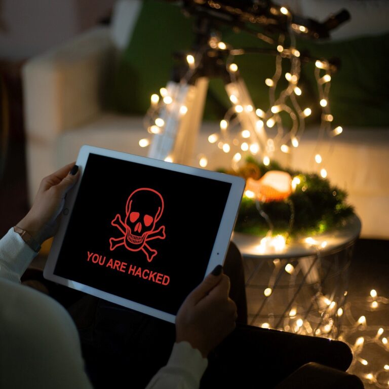 Mann mit einem Tablet in der Hand mit einem Totenkopf und der Aufschrift You Are Hacked in der Weihnachtszeit 