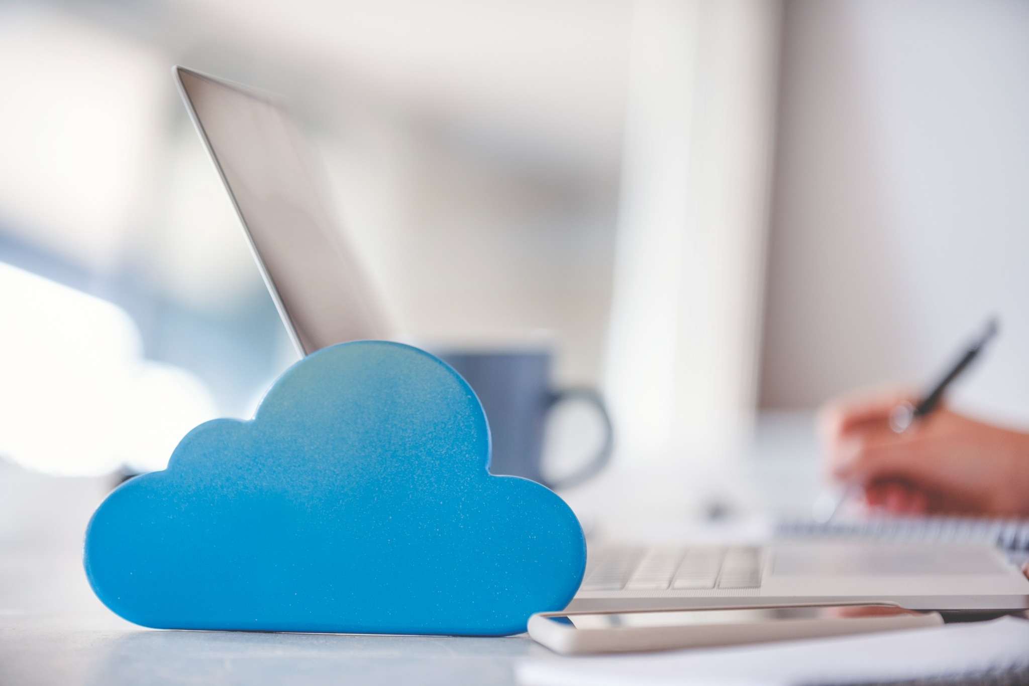 Blaue Wolke steht auf Arbeitsplatz mit Notebook, Smartphone und Tasse