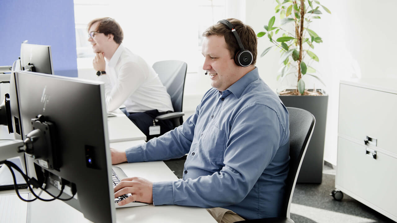 Mitarbeiterinnen die am Telefonieren vor einem Bildschirm sitzen 