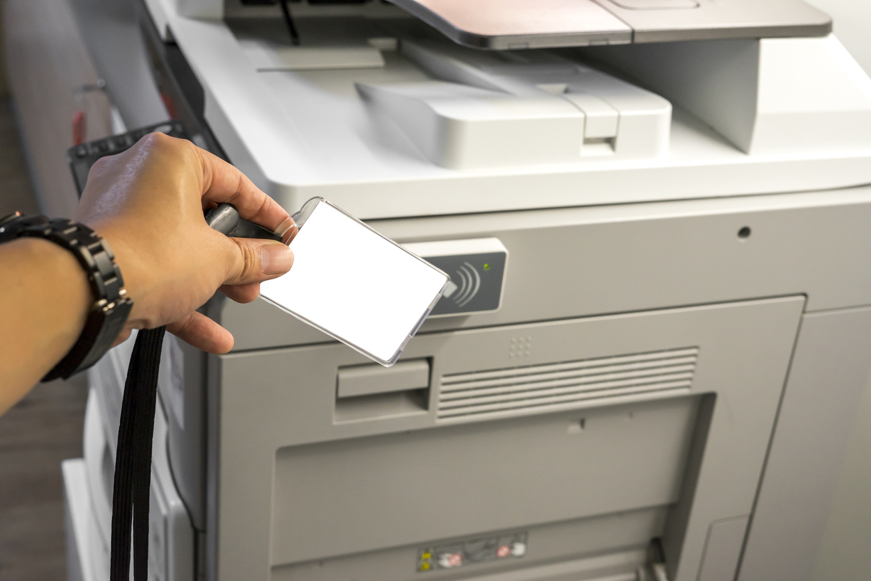 Implementierung von Secure Printing Mitarbeiter hält seinen Personalausweis an einen Drucker, um sich zu authentifizieren