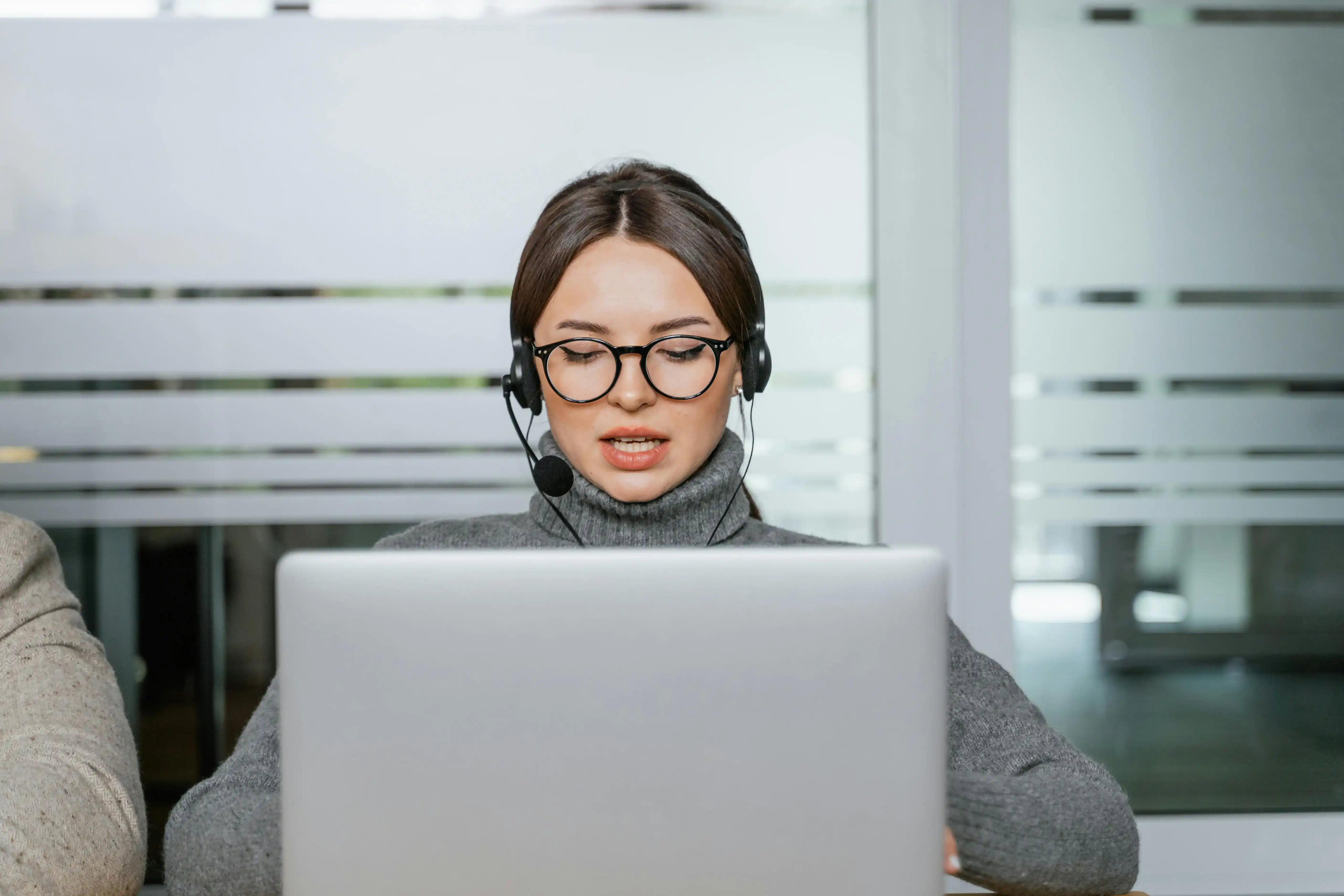 1 IT-Supporter Ticketsystem, Frau mit Headset vor einem Notebook