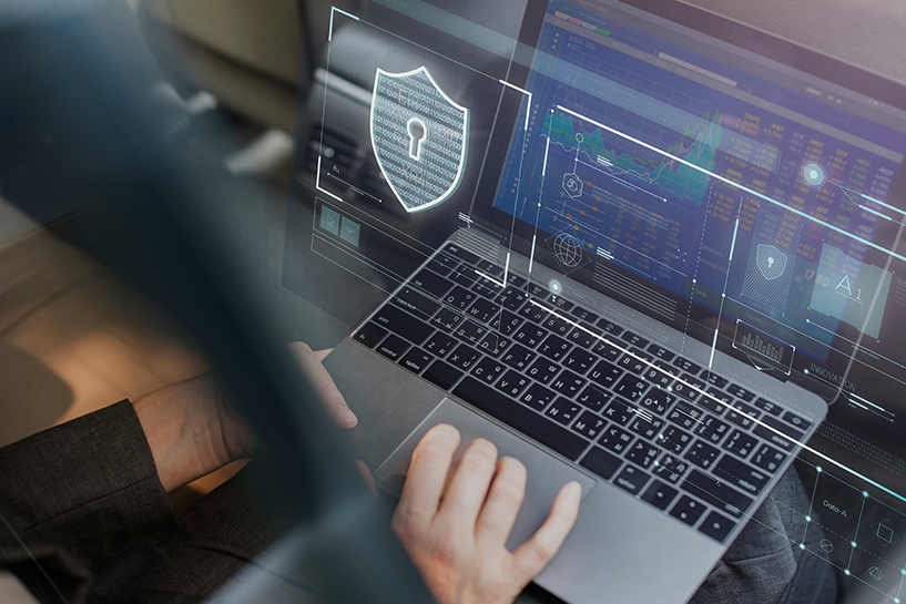 Eine Person hebt ein Laptop auf dem ein Diagramm und verschiedene Daten angezeigt wird, im Vordergrund ein virtuelles Schloss