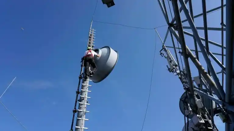 Antenne für Richtfunk, Mann von hinten auf Stufenleiter und blauen Himmel Was ist Richtfunk? Antenne für Richtfunk, Mann von hinten auf Stufenleiter und blauen Himmel