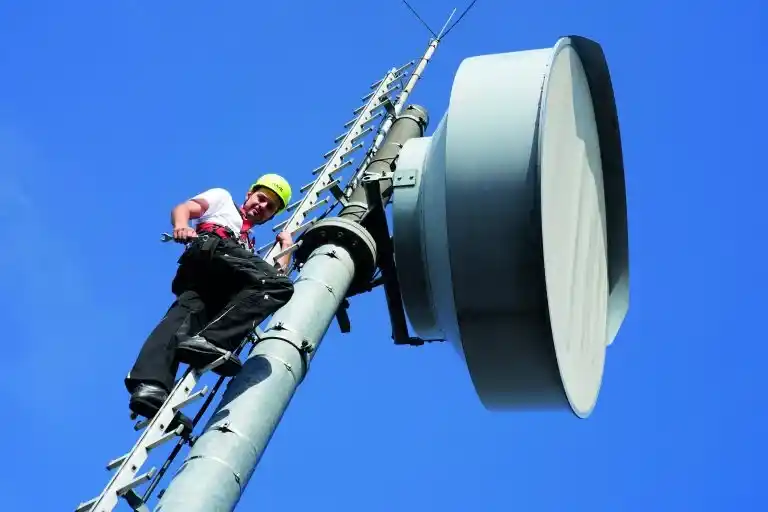 Antenne für Richtfunk, Mann auf Stufenleiter und blauen Himmel