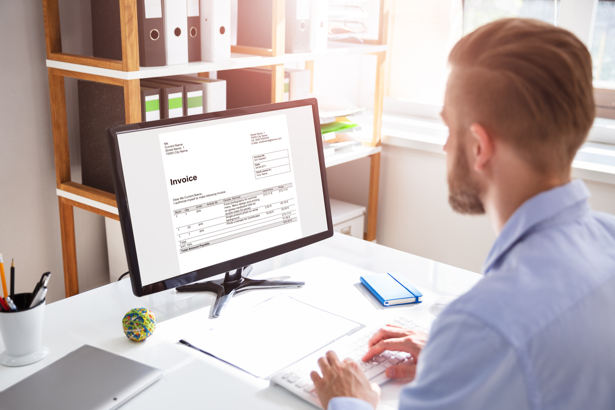 Die neue Regelung zur E-Rechnung Mitarbeiter sitzt vor einem PC-Bildschirm, tippt auf der Tastatur und schaut sich eine E-Rechnung an
