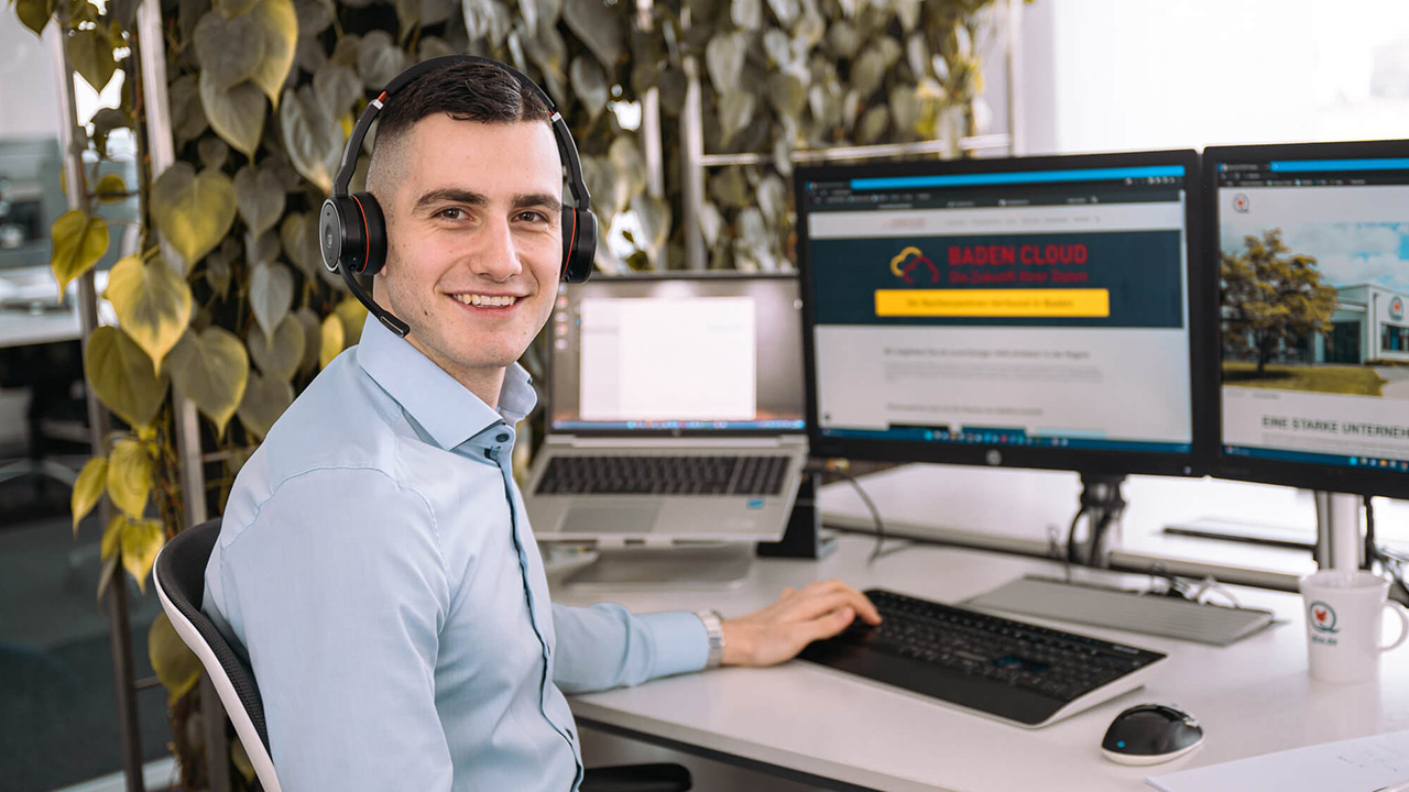 Einstiegsmöglichkeiten bei LEITWERK LEITWERK Mitarbeiter mit Headset am Arbeitsplatz