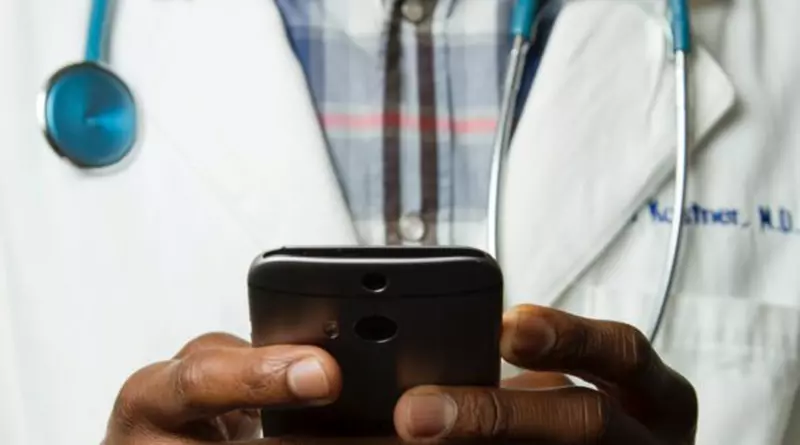 Digitalisierung im Gesundheitswesen Mann mit Arztkittel hält ein Mobiltelefon