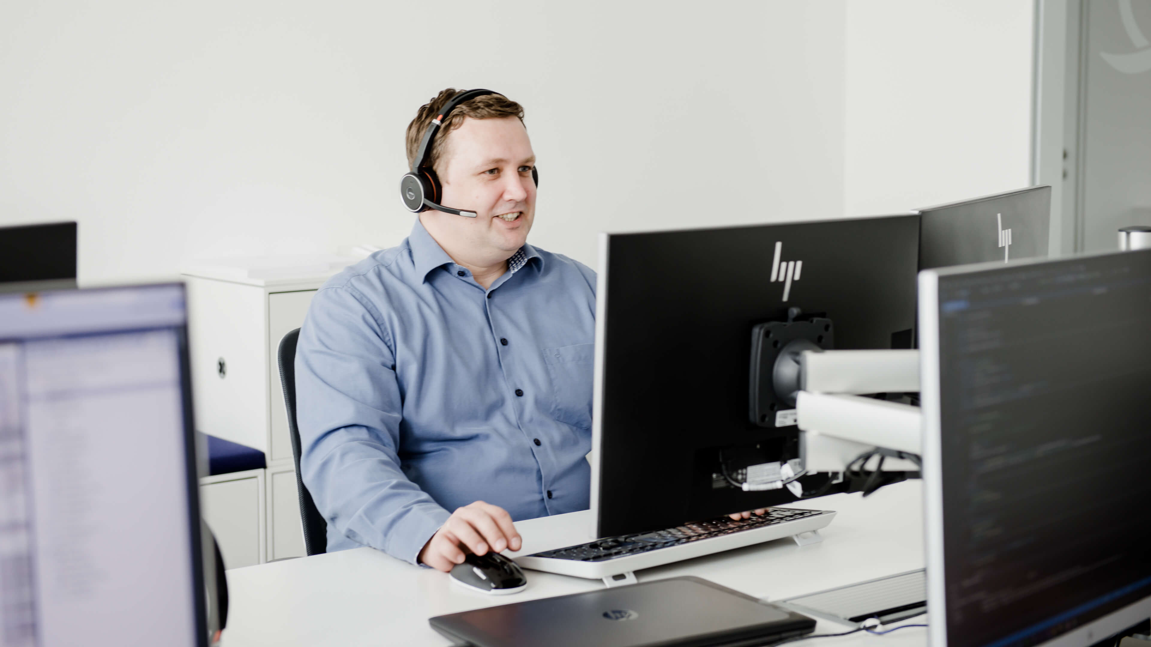 Servicemitarbeiter der LEITWERK AG sitzt an seinem Arbeitsplatz und telefoniert über ein Headset
