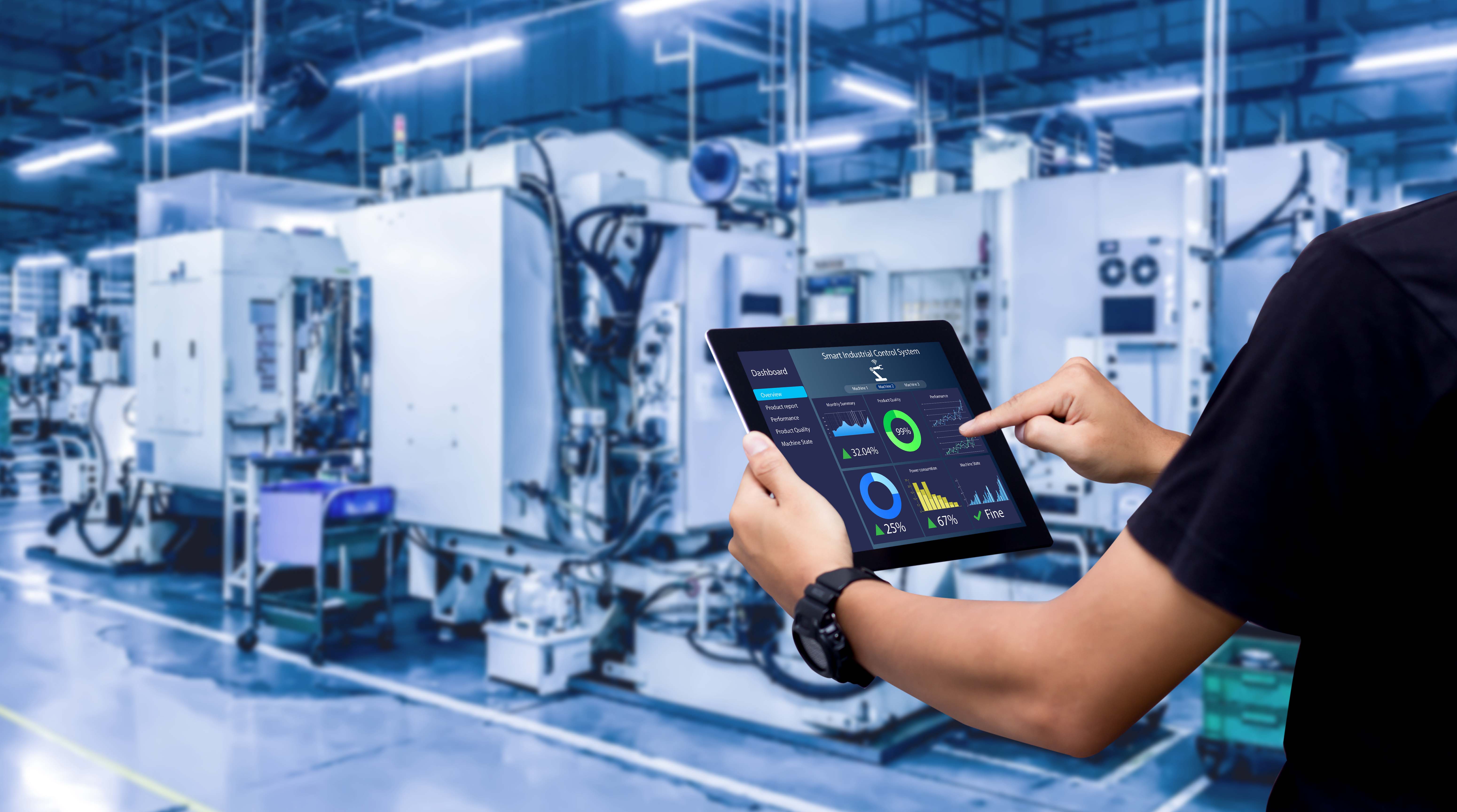 Mitarbeiter hält in einer Industriehalle ein Tablet in der Hand und steuert damit die Produktionsanlage